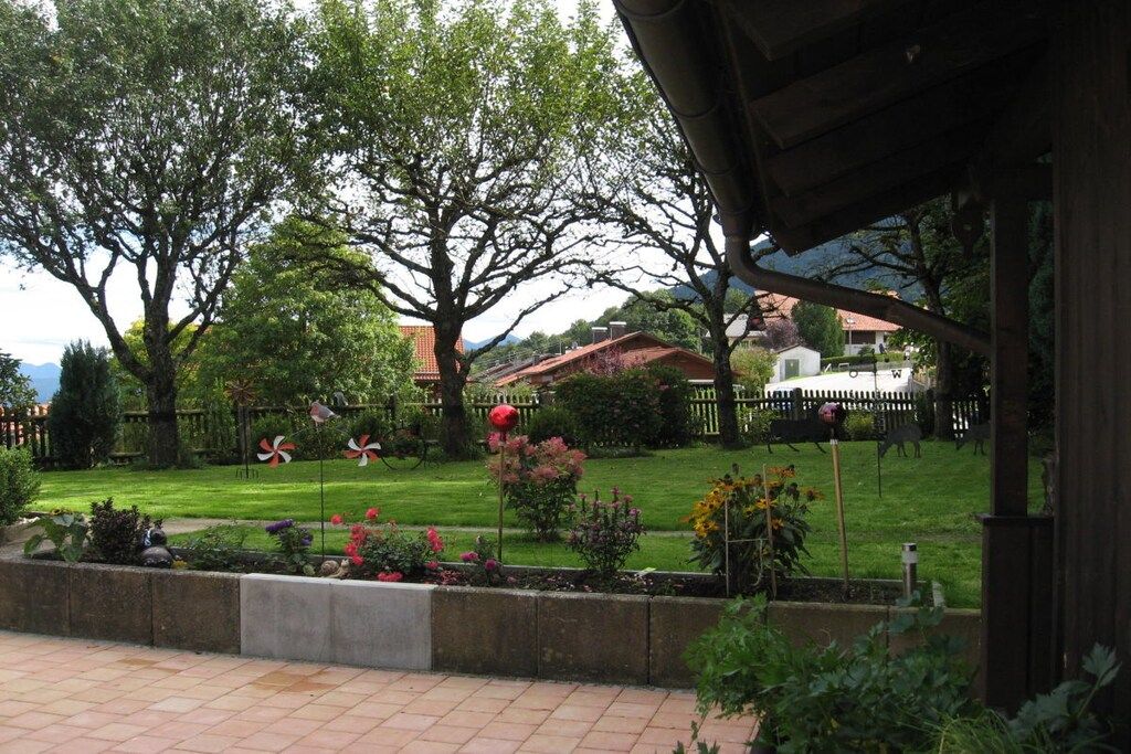 A garden with a wooden pergola, a fenced area with a white fence, and a variety of plants and flowers.