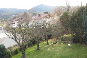 A residential area with houses, a fenced yard, and a mountain in the background. - House by the spa park (Bad Kohlgrub)