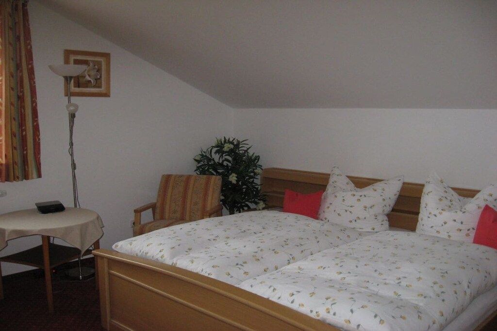 Una camera da letto con un letto, un comodino, una sedia, una lampada e una pianta.