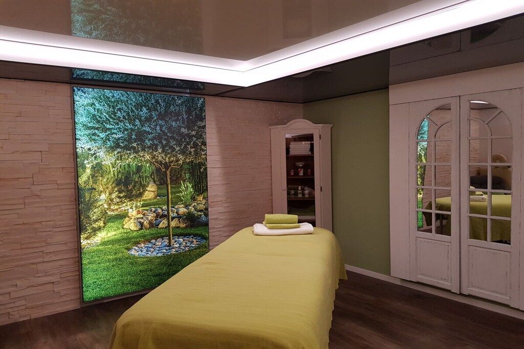 Une chambre comprenant un lit, une armoire et un grand écran fixé au mur, sur lequel est diffusée une scène de la nature.