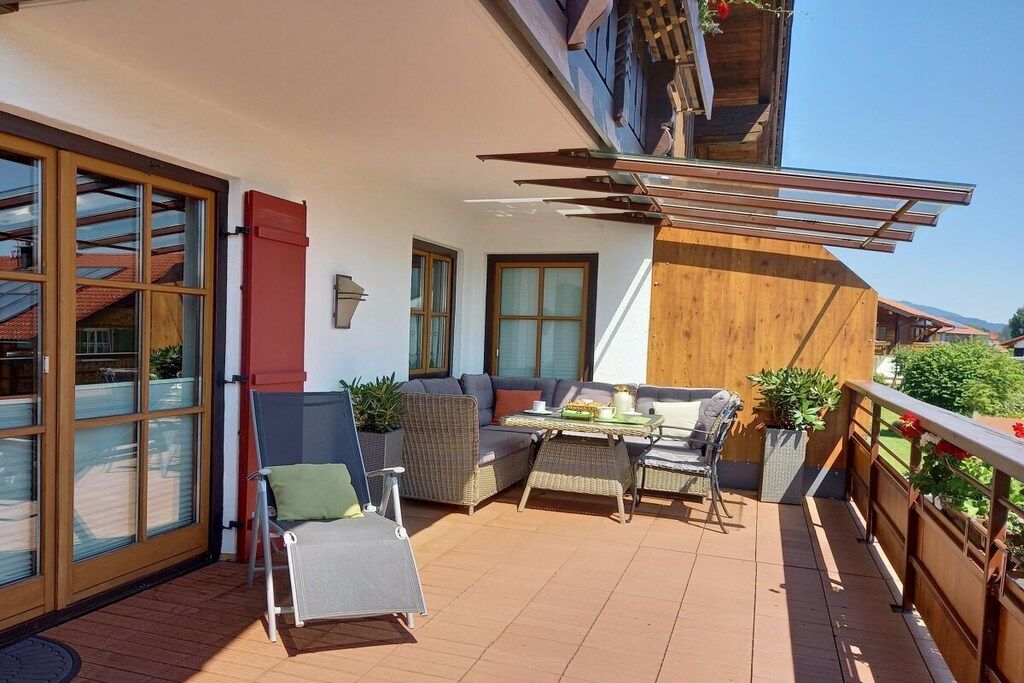 A balcony with a seating area, a table, and potted plants.