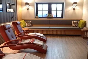A seating area with cushioned chairs and a bench, a window with blinds, and wall-mounted lamps. - Holiday apartment with 3 bedrooms (Bolsterlang)