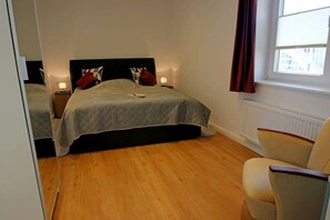 A bedroom with a bed, two bedside tables, a chair, and a window. - Holiday apartment with 1 bedroom (Dollerup)