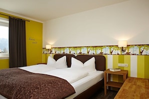 Ein Hotelzimmer mit einem Bett, einem Nachttisch, einer Lampe und einem Fenster mit Vorhängen.