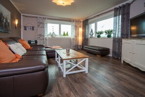 Un salon avec un canapé, une table basse et un téléviseur.