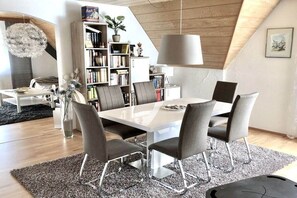 A modern dining area with a white table, grey chairs, and a bookshelf in the background. - At the spa park - Altmühltal (Treuchtlingen)