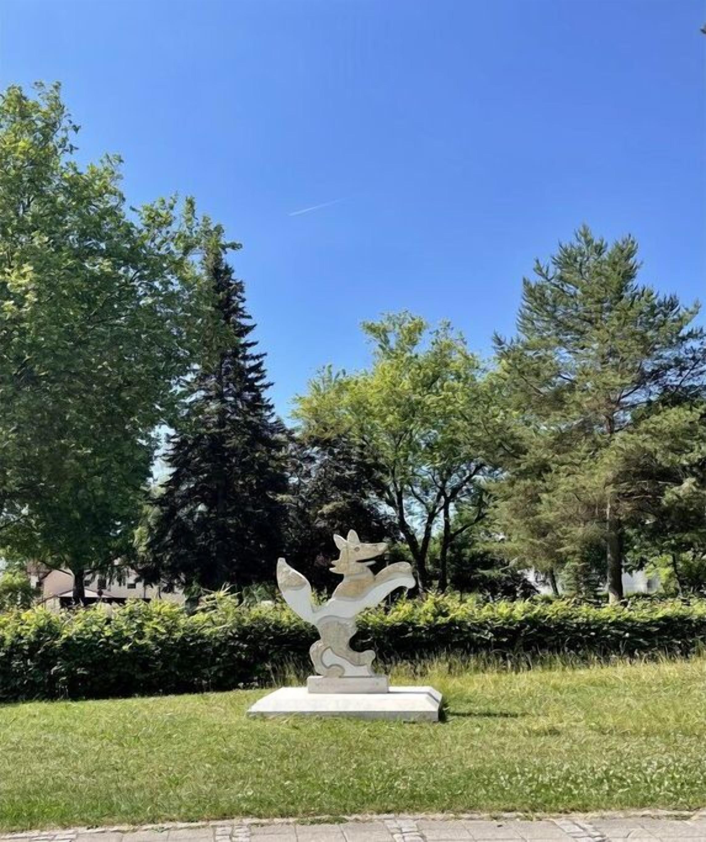 Un parque con una estatua de una criatura mitológica sobre un pedestal.