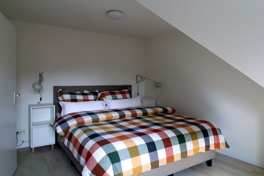 A bedroom with a bed, a nightstand, a lamp, and a door.