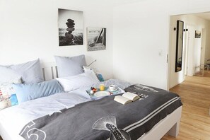 A neatly made bed with a tray of breakfast items, a book, and a pillow with a nautical design. - Holiday apartment with 2 bedrooms (Tönning)