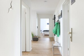Ein Flur mit einer Bank, einem Willkommensschild und einem Kleiderhaken mit einem Mantel.