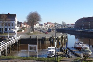 A canal-side view with boats docked, a pedestrian bridge, and buildings along the water. - Holiday apartment with 2 bedrooms (Tönning)