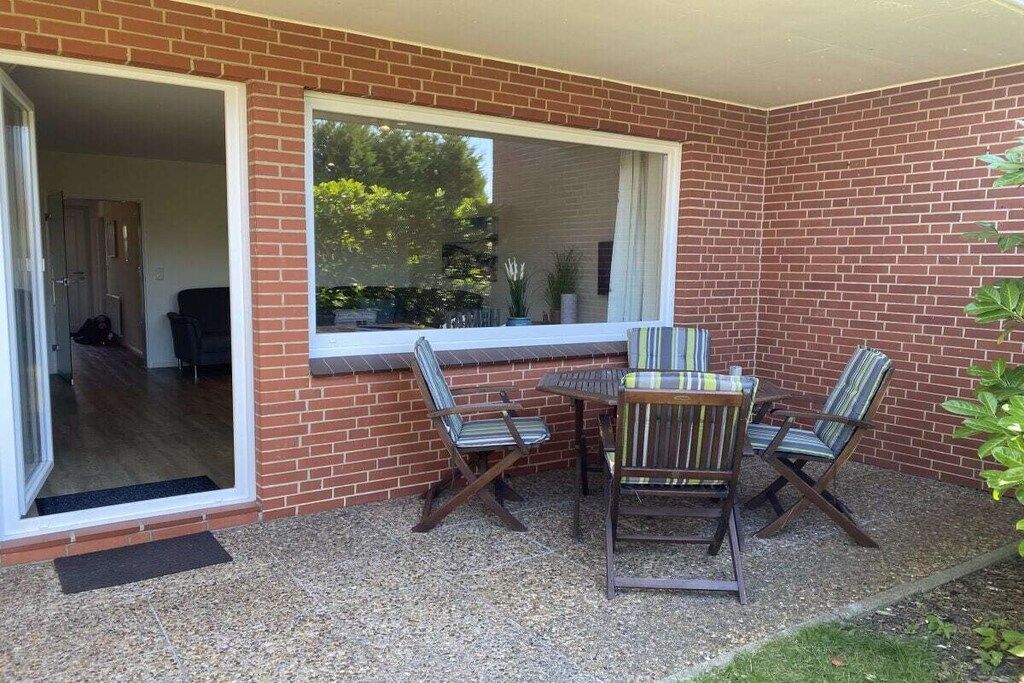 A patio with a brick wall, a sliding glass door, and a table with four chairs.