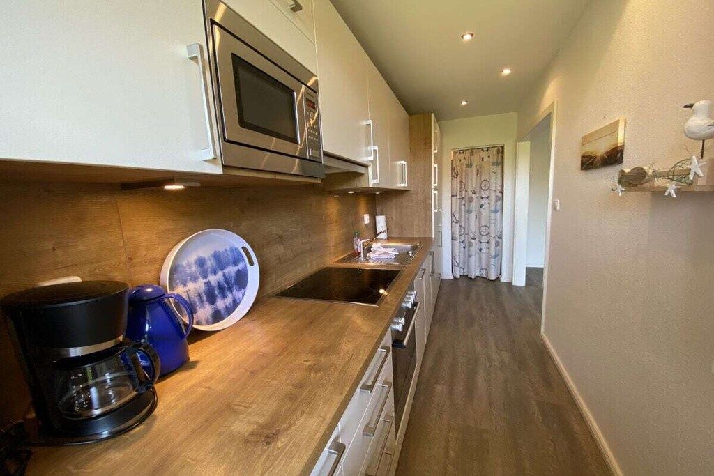A modern kitchen with a microwave, coffee maker, and a sink.