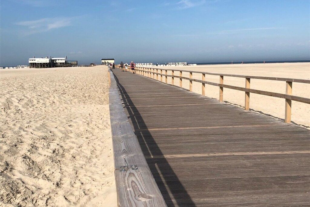 A wooden boardwalk leading to a beach with a clear sky.