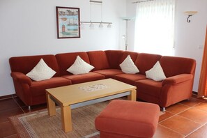 A living room with a red sofa set, a wooden coffee table, and a rug. - Holiday home with 3 bedrooms (Greetsiel)