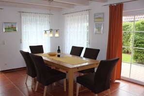 Ein Essbereich mit einem Holztisch, schwarzen Stühlen und einem Fenster mit Vorhängen.