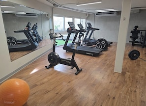 A gym with treadmills, a stationary bike, and a weight bench. - Luxury apartment with spectacular ocean views  —right on the water, with pools, a fitness center, and a rooftop terrace (Jacó)