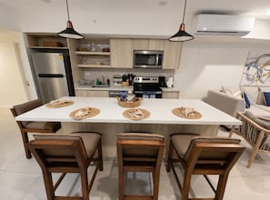 A modern kitchen with a central island, stainless steel appliances, and pendant lighting. - Luxury Condo with Spectacular Ocean Views—oceanfront, pools, gym, rooftop (Jacó)