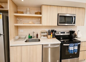 A modern kitchen with stainless steel appliances, wooden cabinets, and a built-in oven. - Luxury apartment with spectacular ocean views—right on the water, with pools, a fitness center, and a rooftop terrace (Jacó)