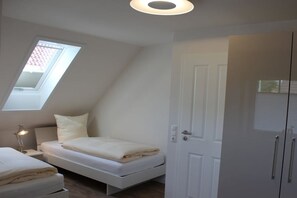 Une chambre avec un puits de lumière, un lit, une table de chevet avec une lampe et une armoire.