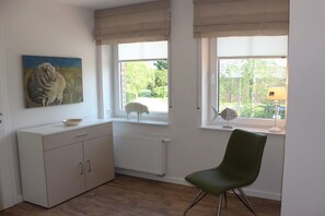 A room with a white cabinet, a green chair, and a painting of a sheep. - Holiday home with 2 bedrooms (Krummhörn-Greetsiel)