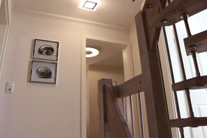 Escada com corrimão de madeira e porta que dá acesso a outro cômodo.
