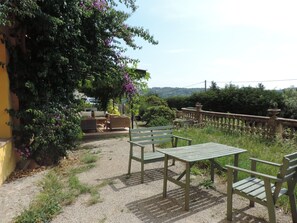 An outdoor seating area with tables and chairs, surrounded by greenery and a view of the countryside. - Charming & large 3-bedroom apartment in Provençal bastide (Grasse)