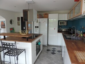 A modern kitchen with a central island, white cabinetry, and a microwave. - Charming & large 3-bedroom apartment in Provençal bastide (Grasse)