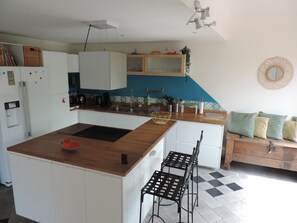 Une cuisine moderne avec des armoires blanches, un plan de travail en bois et une chaise en métal noir.