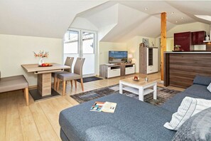 A modern apartment with a dining area, a sofa, a TV, and a kitchen. - Holiday apartment with 1 bedroom (Heringsdorf (Seebad))