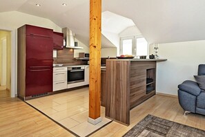 Eine moderne Küche mit einer Holztheke, einem roten Kühlschrank und einem grauen Sofa in einem geräumigen Wohnbereich.
