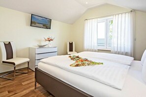 A hotel room with a bed, a desk, a chair, a window with curtains, and a painting on the wall. - Holiday apartment with 1 bedroom (Heringsdorf (Seebad))