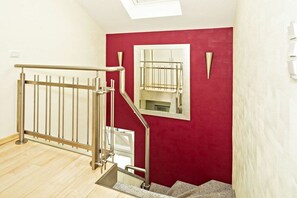 A staircase with a metal handrail, a red wall, and a window. - Holiday apartment with 1 bedroom (Heringsdorf (Seebad))