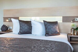Ein Bett mit einem gemusterten Überwurf, einem Kopfteil mit einer Lampe und Zierkissen.