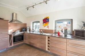 A modern kitchen with a stainless steel range hood, a built-in oven, and a large window providing natural light. - Holiday home with 1 bedroom (Seebad Kölpinsee OT Stubbenfelde)