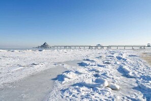 A snow-covered beach with a pier extending into the water. - Holiday home with 1 bedroom (Seebad Kölpinsee OT Stubbenfelde)