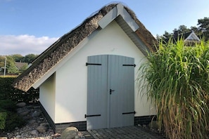 A building with a thatched roof and a grey door. - Holiday home with 1 bedroom (Seebad Kölpinsee OT Stubbenfelde)