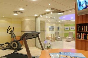 A fitness center with exercise equipment, a glass partition, and a seating area with chairs and a table. - Holiday apartment 2 “Dörchläuchting” (Kühlungsborn)
