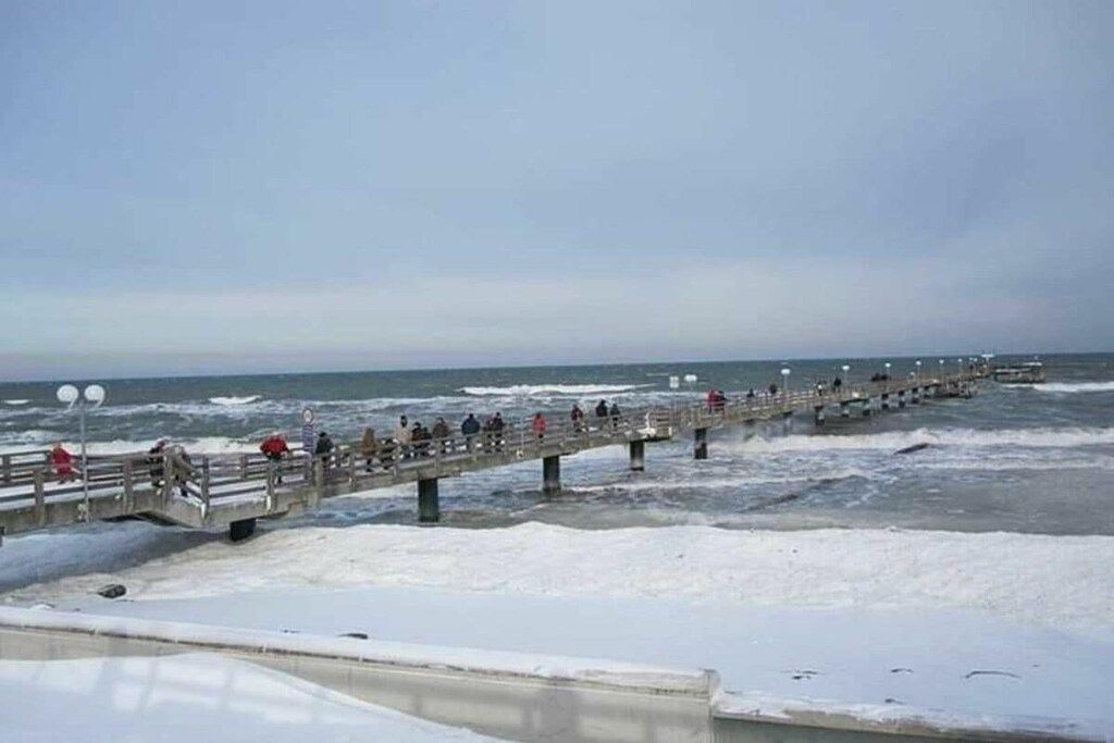 A pier extending into the sea with people walking along it.