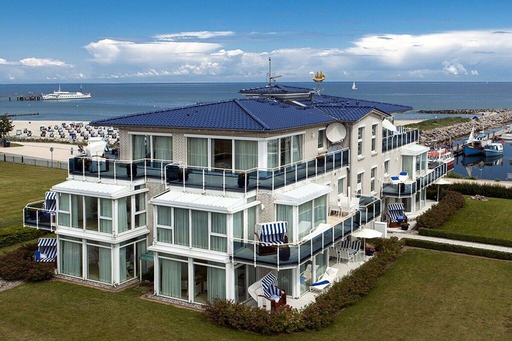 A multi-story waterfront property with balconies, a pool, and a view of the sea.