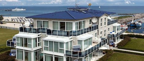 Una propiedad frente al mar con varios pisos, balcones, piscina y vista al océano.