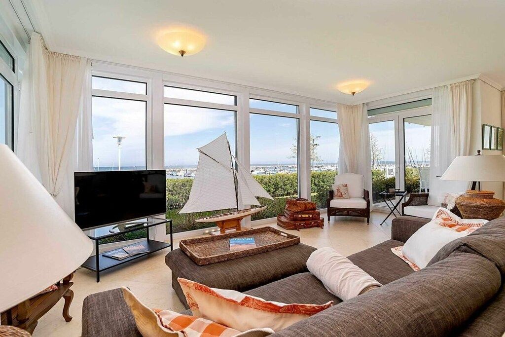 A spacious living room with a large TV, comfortable seating, and a sailboat model.