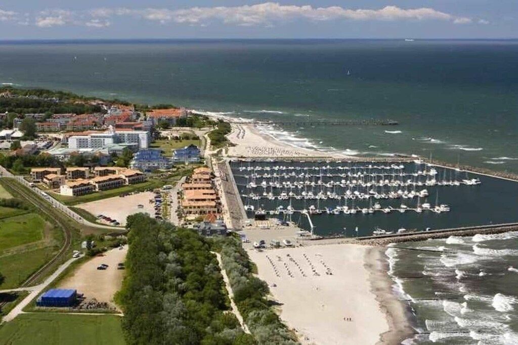 Une zone côtière comprenant un port de plaisance, une plage et des bâtiments.
