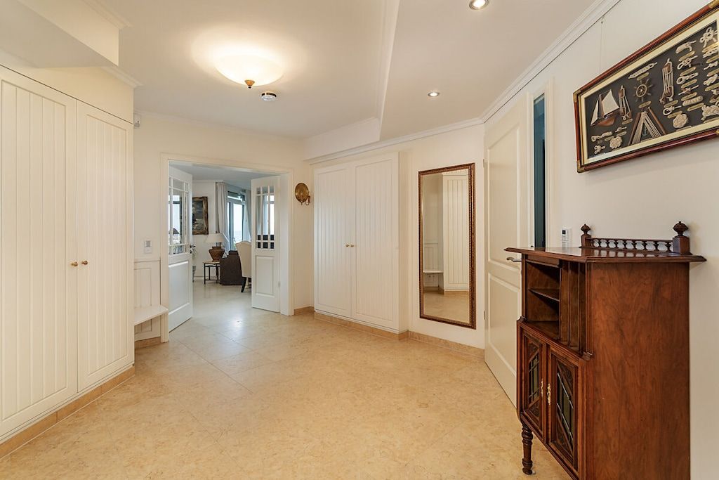 A hallway with white paneling, a wooden cabinet, and a mirror.