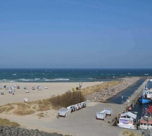 A beach with a row of parked cars, a pier with boats, and a clear sky. - Holiday apartment with 2 bedrooms (Kühlungsborn)