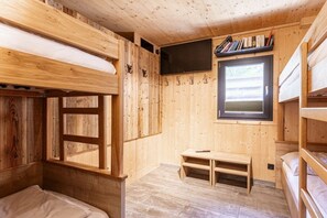 Ein Zimmer in einer Holzhütte mit Etagenbetten, einem Fernseher und einem Fenster.
