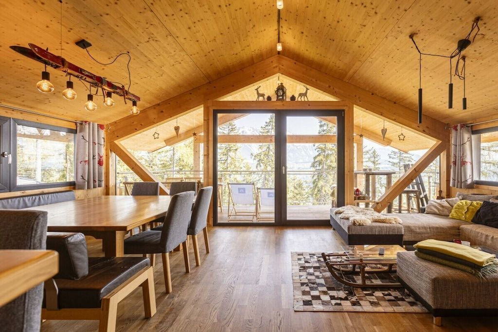 Ein großzügiger Loft-Raum mit hoher Decke, einer Essecke, einer Couch und einer großen Schiebeglasdoor zum Außenbereich.