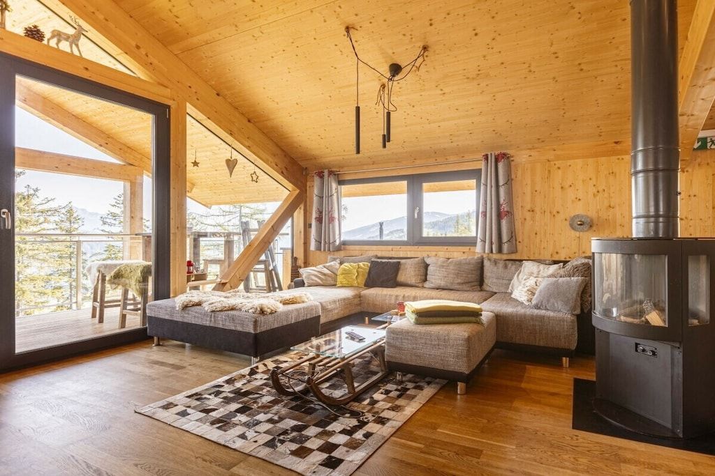 A wooden interior with a sofa, ottoman, and a fireplace.