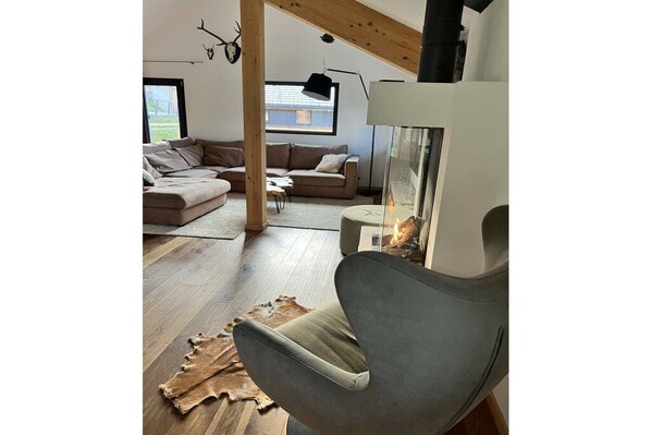 Uma sala de estar moderna com lareira, sofá de couro e uma janela ampla.
