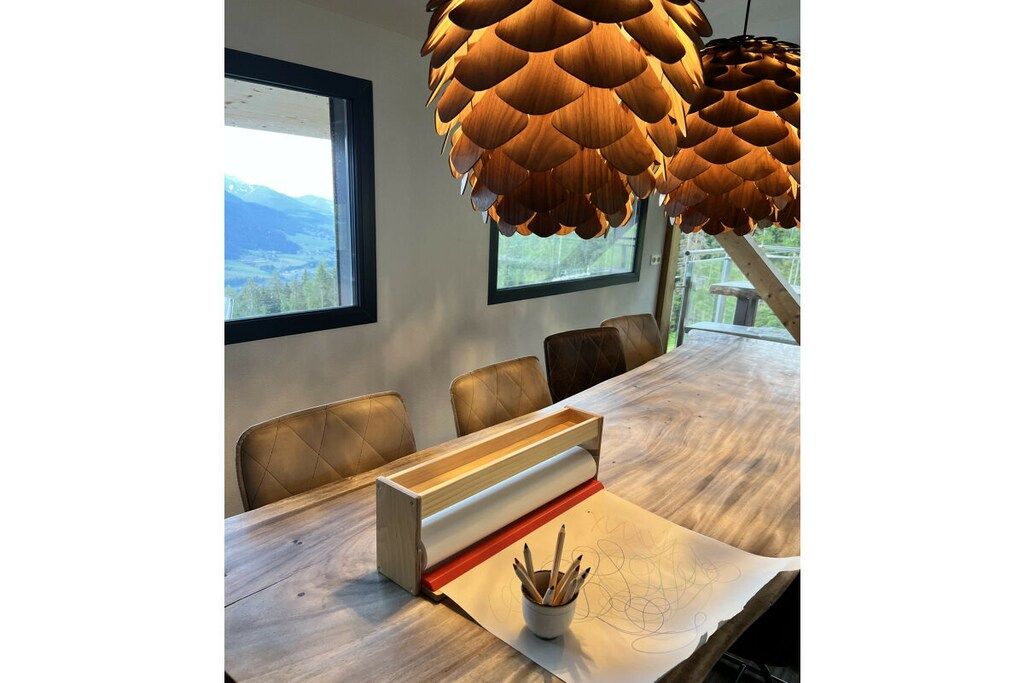Un coin repas avec une table en bois, des chaises et un luminaire suspendu original, également en bois.